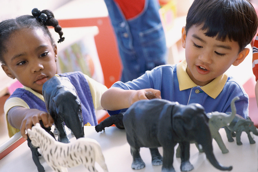 Young boy and girls playing with toy animals together