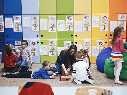 Kids playing with toys with teacher on the floor