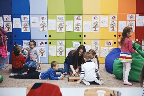 Kids playing with toys with teacher on the floor