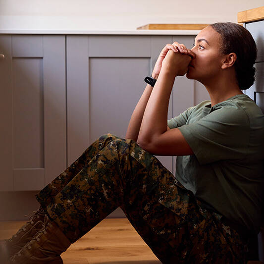 Female Soldier In Uniform Sitting On Kitchen Floor On Home Leave