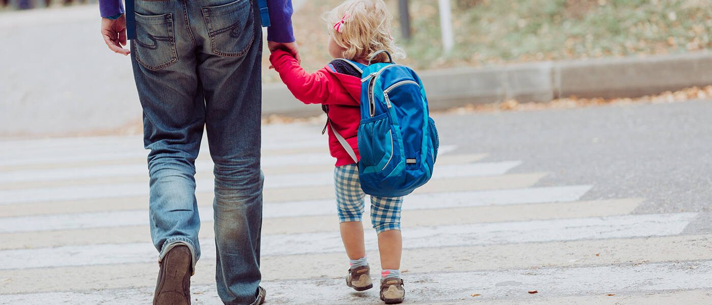 Older kid and young child crossing a crosswalk