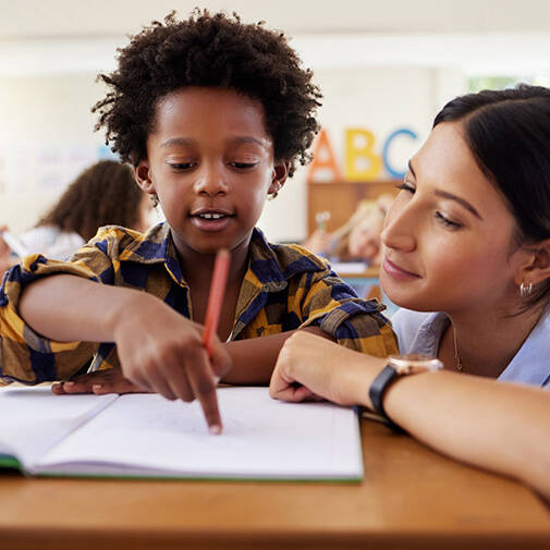 Teacher squatting next to student helping with homework