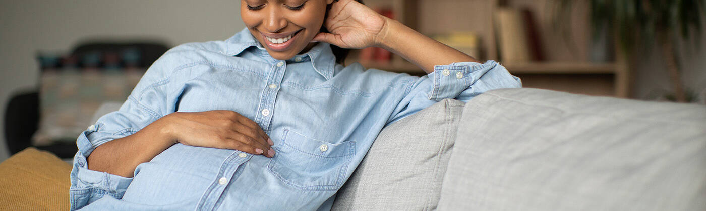 Happy Pregnant African American Woman Smiling Stroking Belly Sit