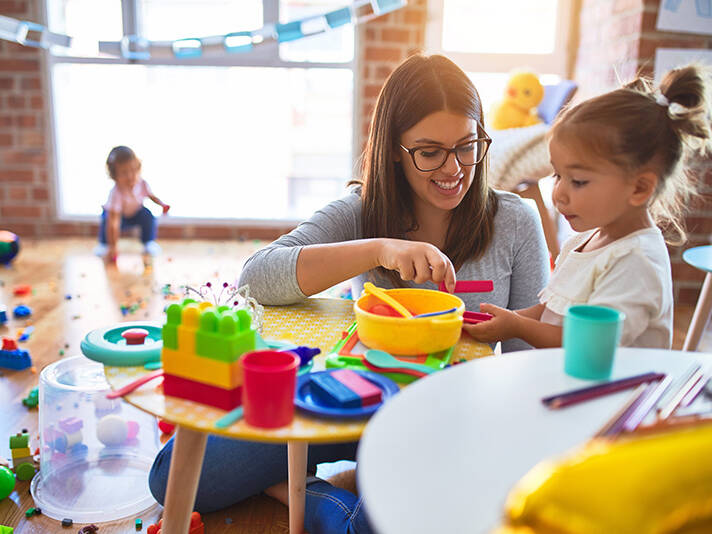 teacher and toddlers playing on the table with lots of toys