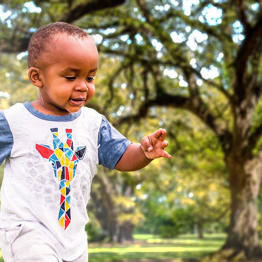 An African American toddler is playing outside on a sunny day
