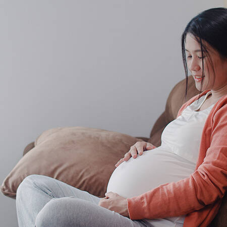 young pregnant mother sitting on the couch